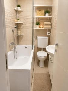 a bathroom with a tub and a toilet and a sink at Lux apartman Ub II in Ub