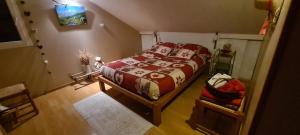 a bedroom with a bed with a red and white blanket at Les Nids de Mesanges Chambre d'hôtes in Selonnet