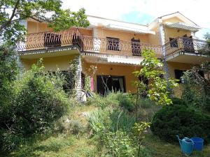 a large yellow house with a balcony on it at Kuća u zelenilu in Poljane