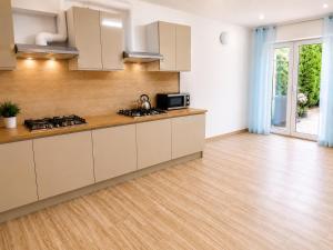 a kitchen with white cabinets and a wooden floor at Obłoczek in Łeba