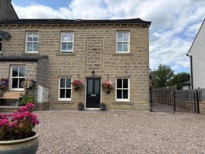 a brick house with a black door and flowers at Hatters Cottage in Bingley