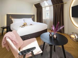 a hotel room with a bed and a chair and a table at Hotel Am Konzerthaus - MGallery Collection in Vienna