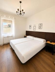 a bedroom with a large white bed and a chandelier at Villa Rural in Cabezuela
