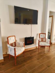 a living room with two chairs and a flat screen tv at Villa Rural in Cabezuela
