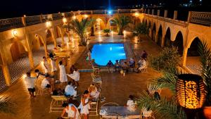 a group of people sitting around a pool at night at Riad Akabar Merzouga in Merzouga