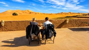 two people sitting at a table in the desert at Riad Akabar Merzouga in Merzouga