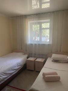 two beds in a small room with a window at Fly Apart in (( Turksib ))