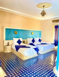 two beds in a room with blue and white at Riad Akabar Merzouga in Merzouga