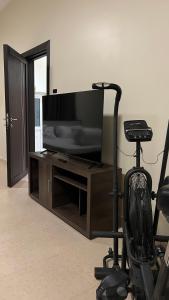 a entertainment center with a television and a chair in a room at Stylish 2BR Escape Near Muscat City Centre in Mawāliḩ