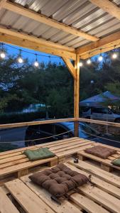 a wooden pergola with two pillows on a deck at Camp & Hostel Maltakva in Poti