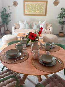 a dining room table with plates and red flowers on it at Quinta Do Priorado in Moncarapacho
