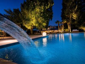 a fountain in front of a swimming pool at night at CasaKadd Grand Escape in Civé