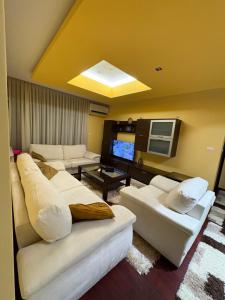 a living room with white couches and a flat screen tv at Apartmani delux in Sarajevo