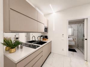 a white kitchen with white cabinets and a sink at CasaKadd Grand Escape in Civé