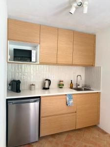 a kitchen with wooden cabinets and a stainless steel dishwasher at Quinta Do Priorado in Moncarapacho +16 photos