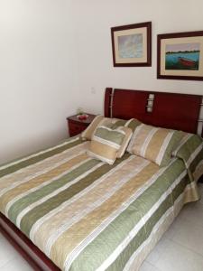 a bedroom with a bed with a green and white comforter at Habitación Conj parque San Agustín, Floridablanca in Floridablanca
