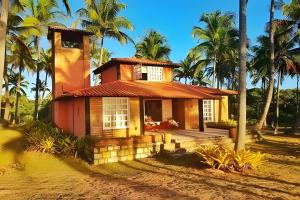 a small house in front of some palm trees at Casa Capela - Para quem ama ficar na beira do mar in Marau