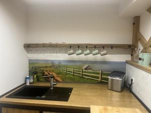 a kitchen with a sink and a farm mural on the wall at Castle view Chalet - ZemvaStays in Zgornje Gorje