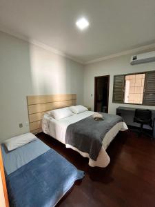 a bedroom with a large bed and a desk at Casa Completa à 100m do Parque de Exposição in Patos de Minas