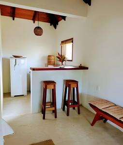 a kitchen with two stools and a counter with a refrigerator at Licuri Praia de Algodões paz amor na beira do mar in Marau