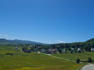 a green field with houses and a road at Sunrise in Žabljak