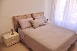 a bedroom with a bed with a night stand and a window at Casa Riviera Chiara con Parcheggio Privato nel Cuore di Arma in Arma di Taggia