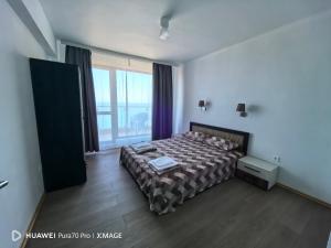 a bedroom with a bed and a large window at Sunrise Apartments in Ahtopol
