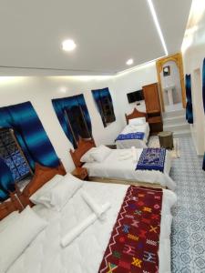 a room with three beds and a red carpet at FATI GUEST HOUSe in Chefchaouen