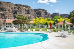 a swimming pool with chairs and tables and mountains in the background at #13 Condo near large pool-Gorge shuttle-book separately in Quincy