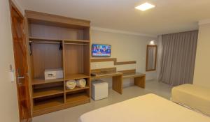 a room with a bedroom with a bed and a tv at Vitoria Regia Praia Hotel in Porto Seguro