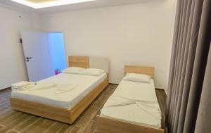 two twin beds in a room with a window at Vila Qetesia in Përmet