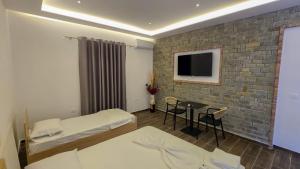 a hotel room with two beds and a table and a tv at Vila Qetesia in Përmet +8 photos