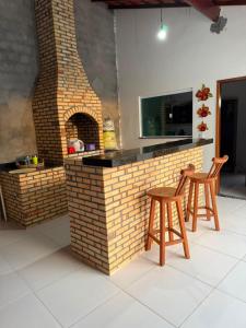 a brick bar with two stools and a fireplace at pousada ilha do amor in Barreirinhas