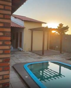 a house with a swimming pool in front of a sunset at pousada ilha do amor in Barreirinhas