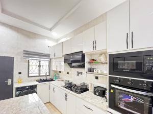 a kitchen with white cabinets and a stove top oven at Domina Serviced Apartment in Kubwa