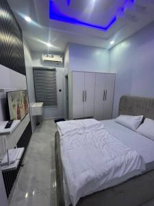 a bedroom with a white bed and a blue light at Domina Serviced Apartment in Kubwa