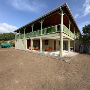 a large white house with a balcony and chairs at Villa Floru in Le Carbet