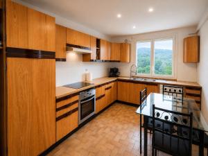 a kitchen with wooden cabinets and a table in it at Ciné Lodge Lourdes in Lourdes