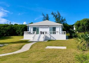 a white house with a porch and a lawn at The Anchorage at Rainbow Bay, Eleuthera in Hatchet Bay Limited Settlement