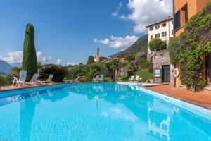 a large swimming pool with a house and mountains in the background at Brentano Giardino in Mezzegra
