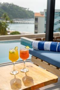 two drinks on a wooden table next to a pool at EOS Suites in Santa Cruz Huatulco