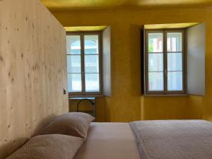 a bedroom with two windows and a bed with pillows at Casa Piumogna in Faido