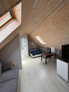 an attic room with a couch and a bed and a tv at Pensjonat Dom Latarnika in Grzybowo