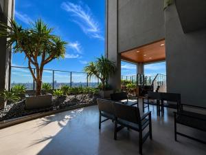 a patio with tables and chairs and palm trees at Vertigo Premium Studios in Campo Grande