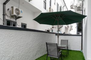 a green umbrella sitting on a patio with two chairs at Luxe Haven in Lekki