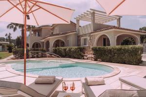 a house with a swimming pool and an umbrella at Appartamenti I Lentischi in Villasimius
