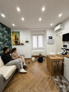 Eine Gruppe von Menschen sitzt auf einem Sofa in einem Wohnzimmer. in der Unterkunft Maison Frattasio in Neapel