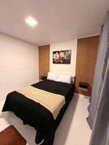 a bedroom with a large bed with a black blanket at Recanto dos pássaros in Guapimirim