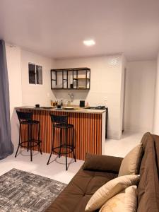 a living room with a couch and a bar with stools at Recanto dos pássaros in Guapimirim