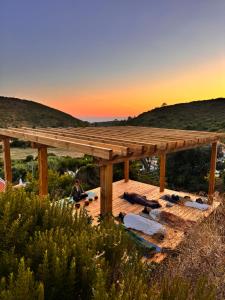a man sitting under a wooden pavilion with the sunset in the background at Casa Nabia - Coastal Sanctuary in Ericeira +20 photos